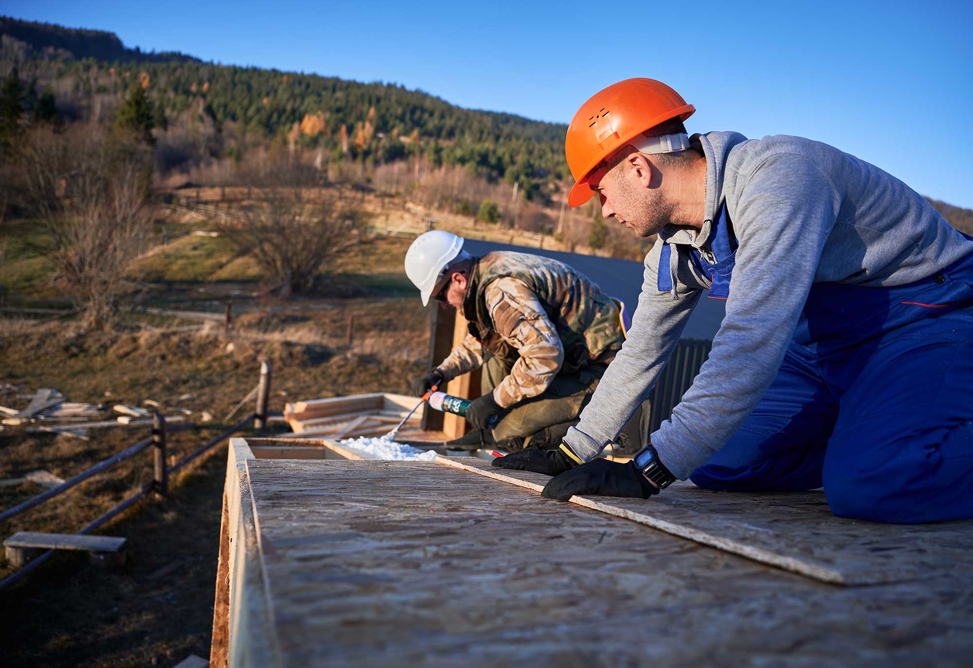 Two men working together to construct a wooden deck in a residential area