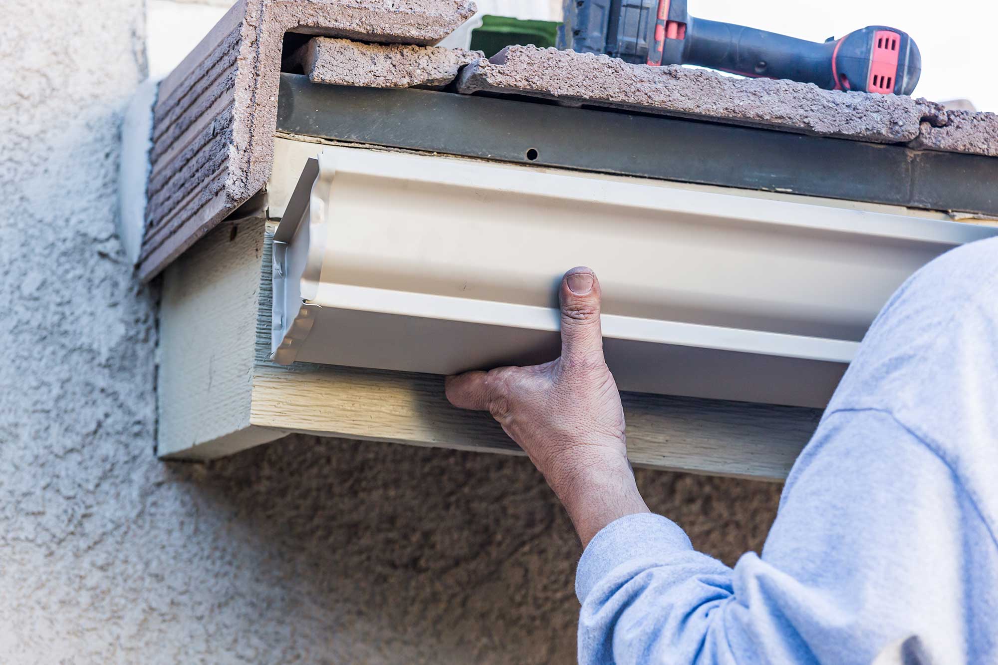 Worker attaching aluminum rain gutter